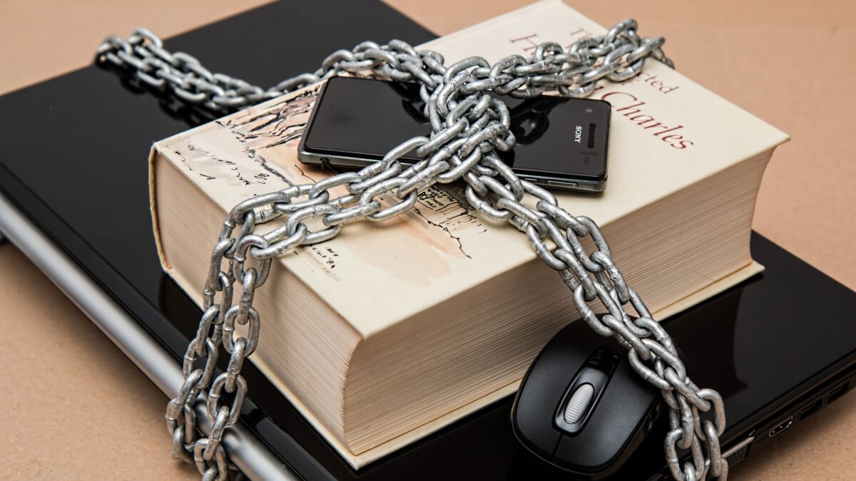 Chain-locked book, phone, and laptop symbolizing digital and intellectual security.