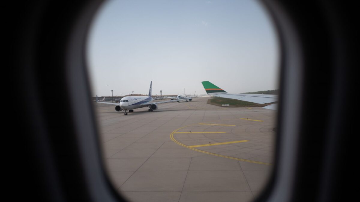 Airplane seen through a window, parked on the airport runway, capturing a travel moment.