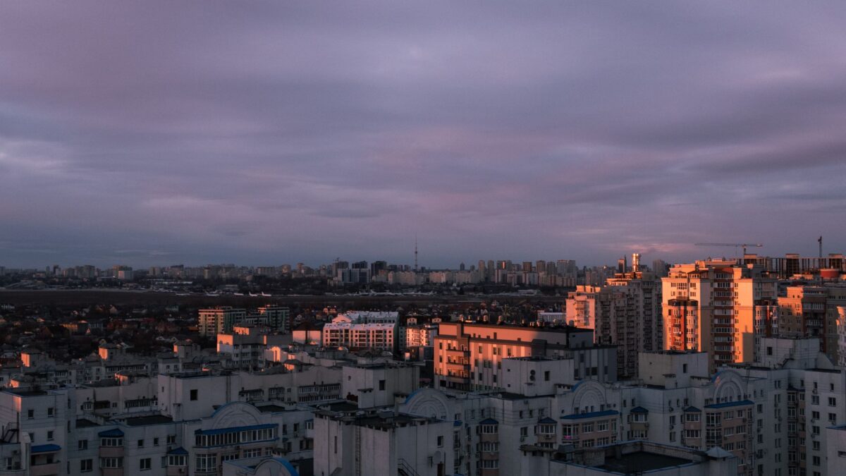 Aerial view of Kyiv city with striking clouds and sunset light over the urban skyline.