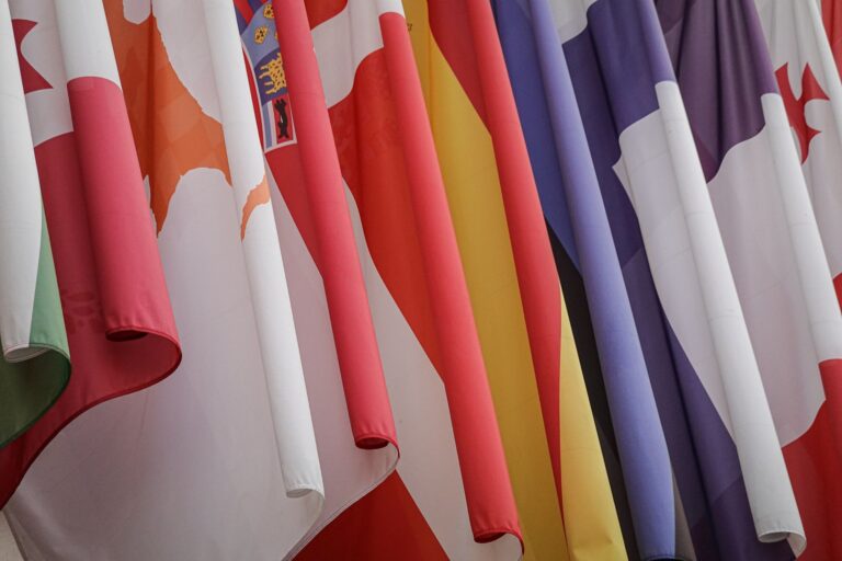 Vibrant display of various international flags closely hanging together.