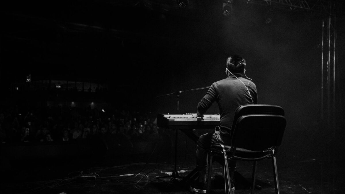 A musician playing piano on stage at a live concert. Captivating atmosphere.